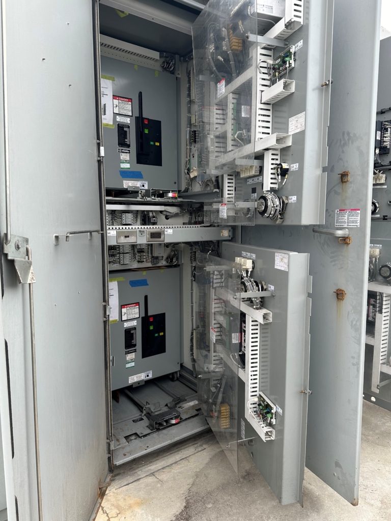 Open electrical control panel with circuit breakers, wiring, and components visible, showing detailed internal hardware and circuitry.