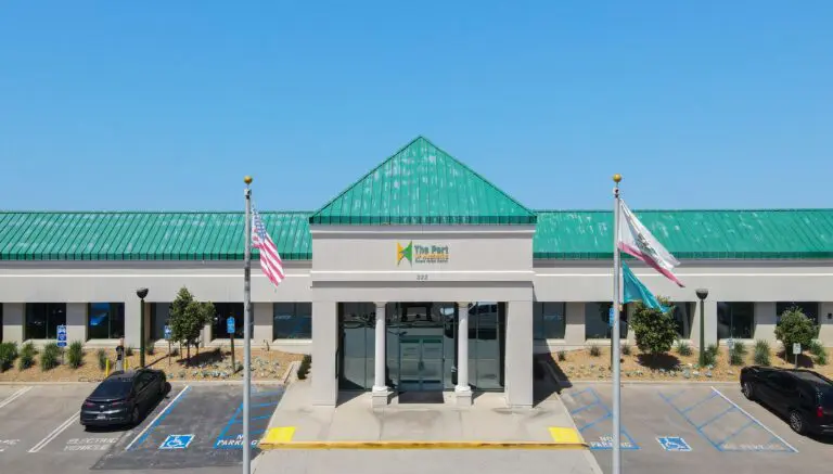 A building with a green roof labeled “The Port” stands proudly, its two flagpoles and accessible parking out front reflecting the $3.935 Million State Grant for Port of Hueneme as California ramps up its Port Data Partnership Program.