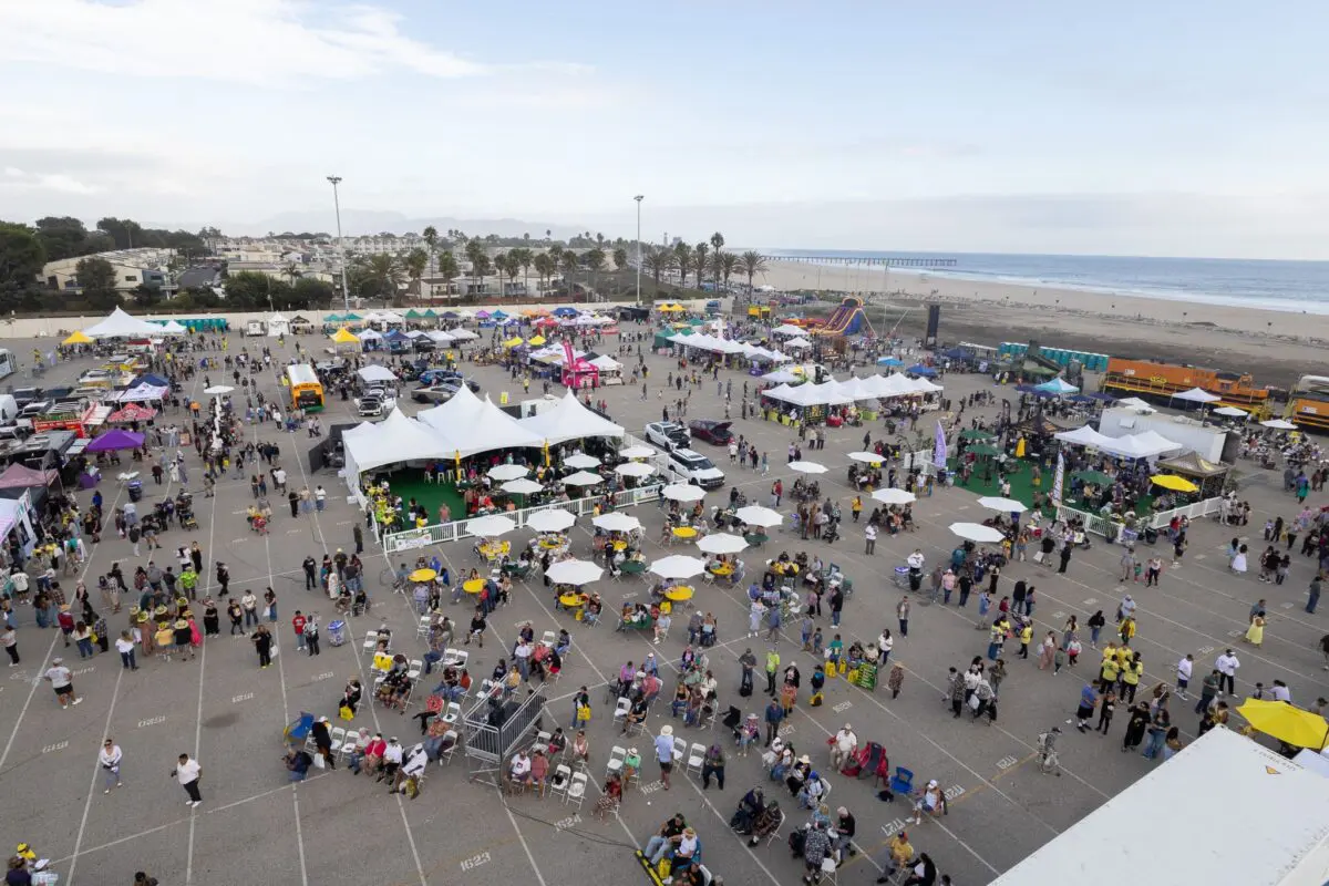 A large outdoor event with tents, food trucks, and crowds of people in a parking lot near the beach and pier celebrates the $3.935 Million State Grant for Port of Hueneme as Governor ramps up the California Port Data Partnership Program.