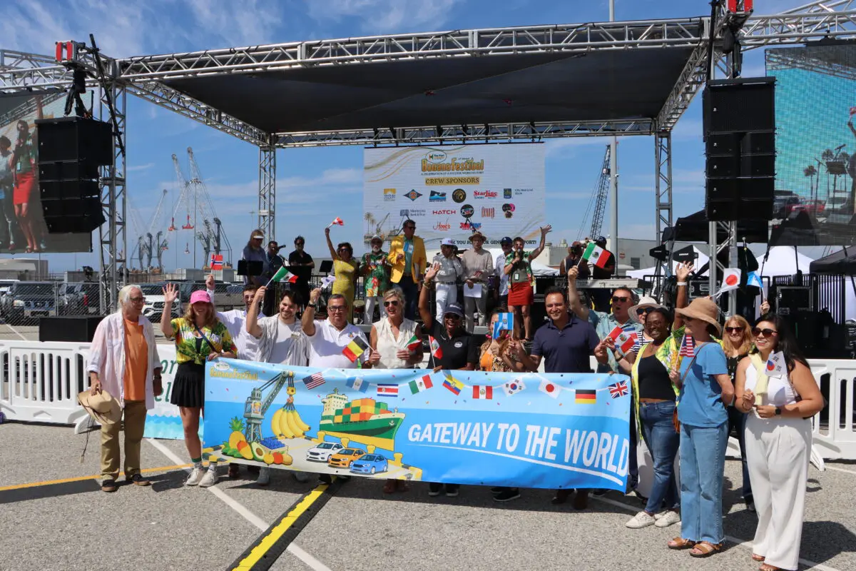 A group of people hold a small international flags and hold a banner with text reading GATEWAY TO THE WORLD.