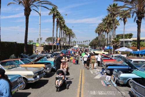 People walk through a line of parked classic cars.