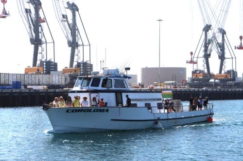 A small boat carries about 20 passengers in the harbor.